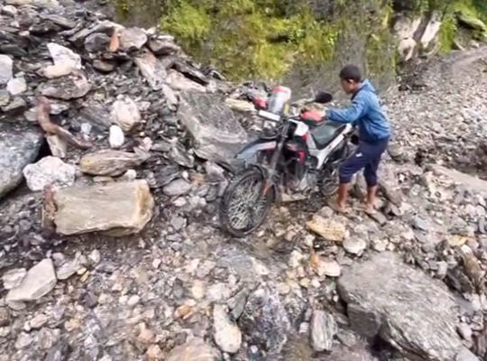 Torrential Havoc: Roads destroyed in Kapkot and the Bhadratunga route blocked; villagers forced to risk their lives navigating their bikes through surging debris.